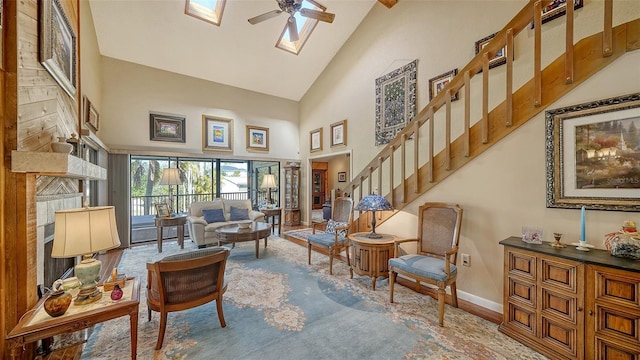 living area featuring high vaulted ceiling, a skylight, a ceiling fan, baseboards, and stairs