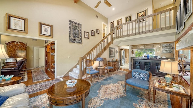 living room with stairs, a high ceiling, visible vents, and baseboards