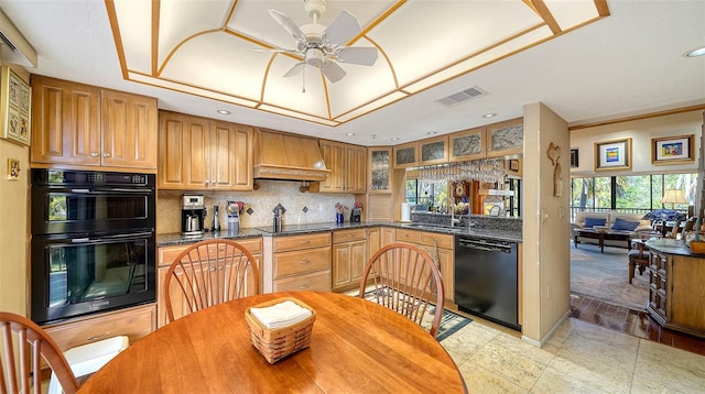 kitchen featuring visible vents, custom exhaust hood, black appliances, a raised ceiling, and glass insert cabinets