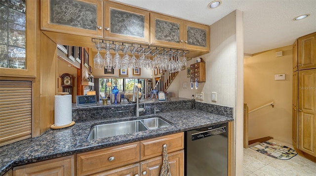 kitchen with glass insert cabinets, brown cabinetry, a sink, dark stone countertops, and dishwasher