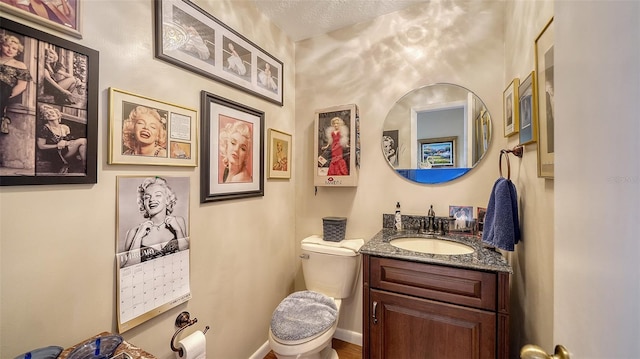 bathroom with toilet, baseboards, a textured ceiling, and vanity