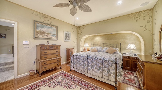 bedroom featuring a ceiling fan, baseboards, arched walkways, and wood finished floors