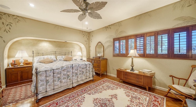 bedroom featuring a ceiling fan, baseboards, wood finished floors, and a textured wall