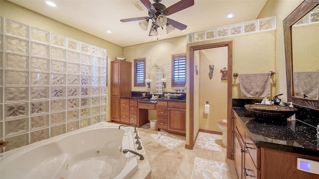 full bath with toilet, a tub with jets, a ceiling fan, and vanity