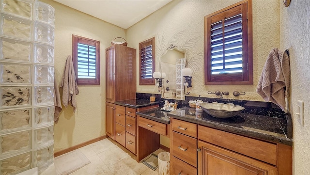 bathroom with a textured wall, tile patterned floors, vanity, and baseboards