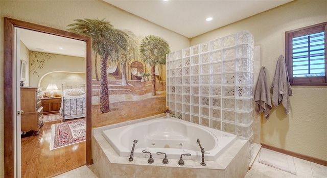 bathroom featuring a jetted tub, tile patterned floors, baseboards, and ensuite bathroom