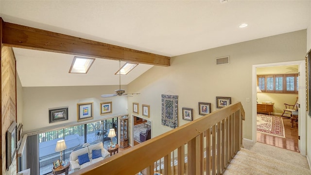 hall featuring light carpet, a skylight, visible vents, beamed ceiling, and an upstairs landing