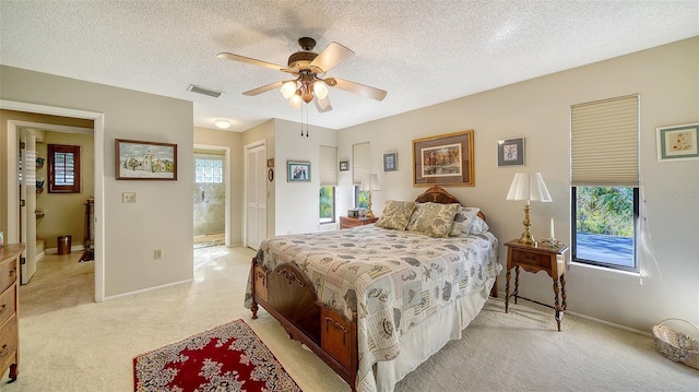 bedroom featuring a textured ceiling, light carpet, visible vents, baseboards, and a closet