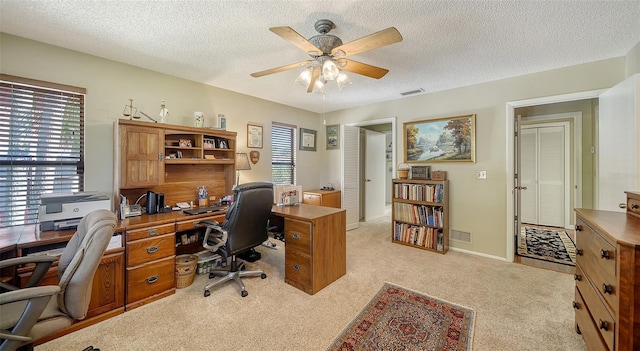 home office with visible vents, ceiling fan, light carpet, and a textured ceiling