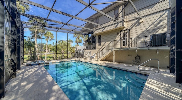 view of swimming pool featuring stairway, a lanai, and a pool with connected hot tub