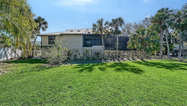 back of house with metal roof, a yard, and glass enclosure