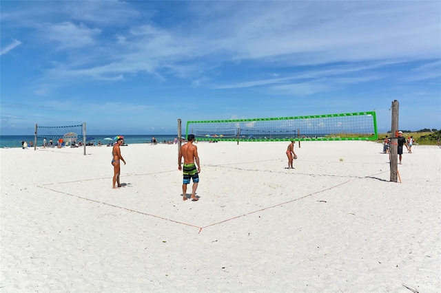 view of property's community with volleyball court, a water view, and a view of the beach