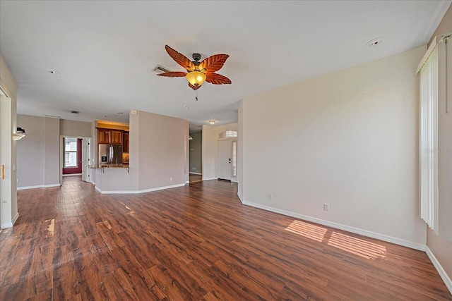 unfurnished living room featuring dark wood-style floors, ceiling fan, visible vents, and baseboards