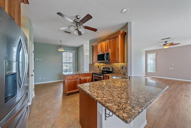 kitchen featuring a peninsula, brown cabinets, visible vents, and stainless steel appliances