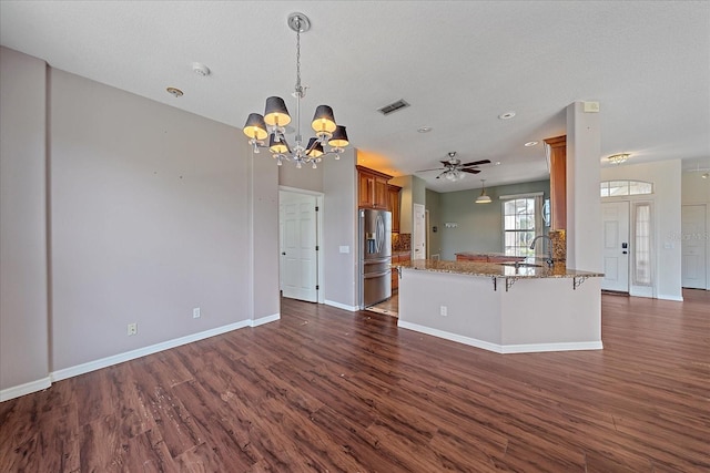 kitchen featuring brown cabinetry, dark wood finished floors, stainless steel refrigerator with ice dispenser, and a peninsula