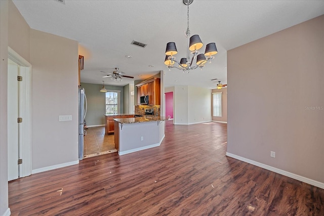 kitchen featuring dark wood finished floors, stainless steel appliances, visible vents, brown cabinetry, and open floor plan