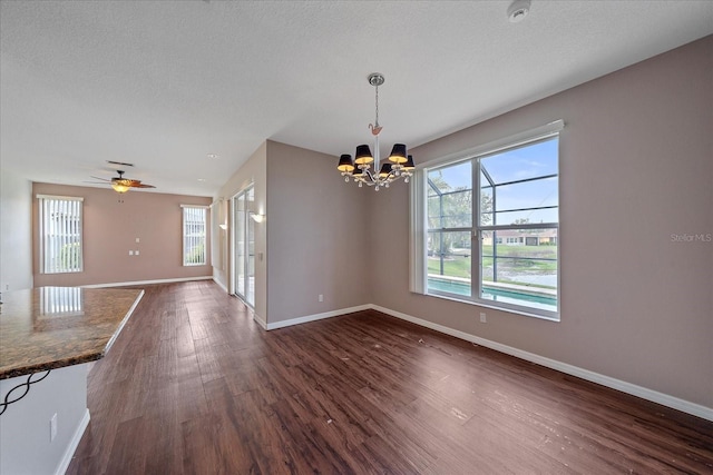 interior space featuring dark wood-style floors, baseboards, a textured ceiling, and ceiling fan with notable chandelier