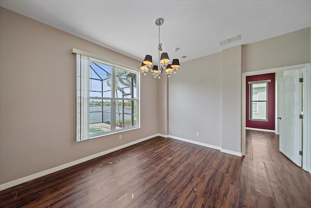 empty room featuring a textured ceiling, a chandelier, visible vents, baseboards, and dark wood-style floors