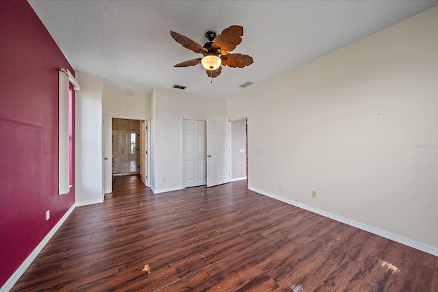 unfurnished bedroom featuring a textured ceiling, dark wood-type flooring, visible vents, and baseboards