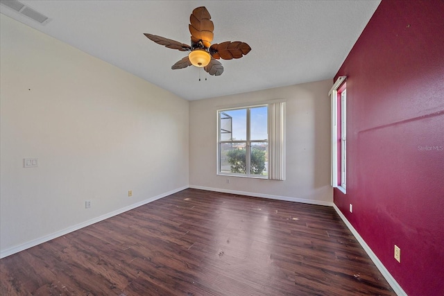 unfurnished room with a ceiling fan, wood finished floors, visible vents, and baseboards