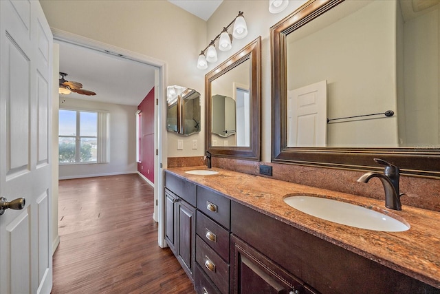 bathroom with double vanity, a sink, baseboards, and wood finished floors