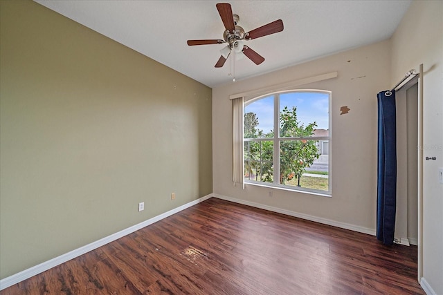 empty room featuring dark wood-style floors, ceiling fan, and baseboards