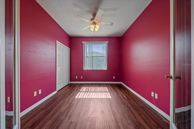 spare room with a textured ceiling, baseboards, and wood finished floors