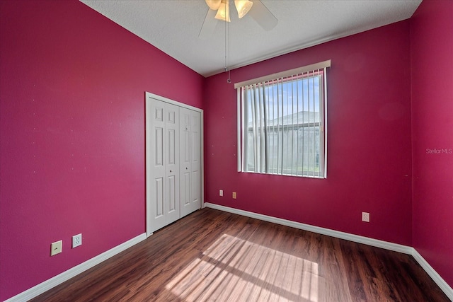 unfurnished bedroom featuring a textured ceiling, wood finished floors, a ceiling fan, baseboards, and a closet