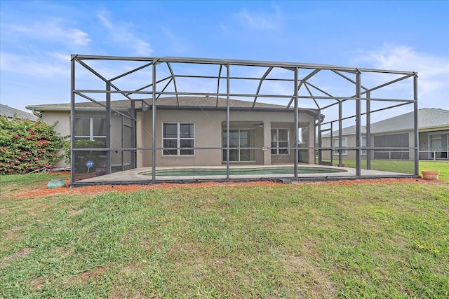 back of property featuring an outdoor pool, glass enclosure, a yard, and stucco siding