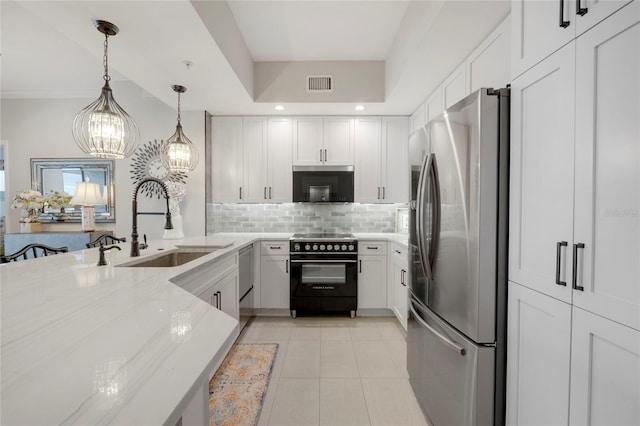 kitchen with tasteful backsplash, appliances with stainless steel finishes, light stone counters, white cabinetry, and a sink