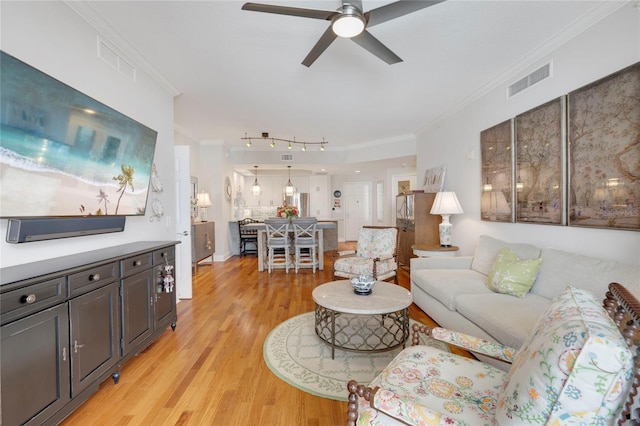 living area featuring a ceiling fan, light wood-type flooring, visible vents, and crown molding