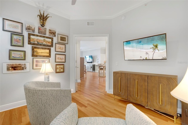 living area with light wood finished floors, ornamental molding, visible vents, and baseboards