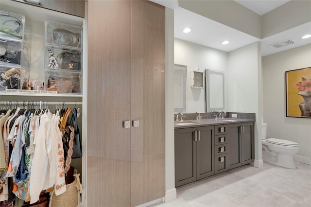 bathroom featuring visible vents, a sink, toilet, and double vanity