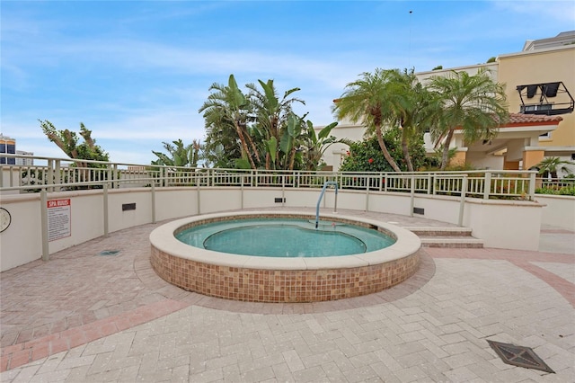 view of swimming pool featuring fence and a hot tub