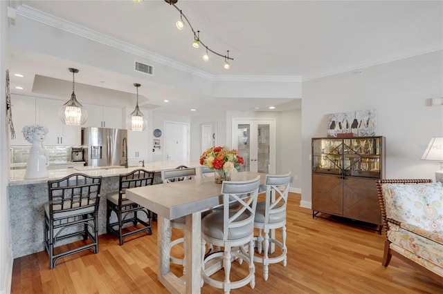 dining room with visible vents, baseboards, light wood-style floors, french doors, and ornamental molding