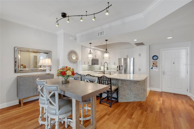 dining area with ornamental molding, light wood-type flooring, visible vents, and baseboards