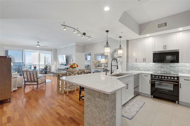 kitchen featuring visible vents, a peninsula, a sink, black electric range, and backsplash