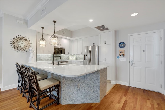 kitchen with visible vents, a breakfast bar area, appliances with stainless steel finishes, a peninsula, and a sink