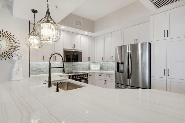 kitchen featuring appliances with stainless steel finishes, backsplash, a sink, and light stone countertops