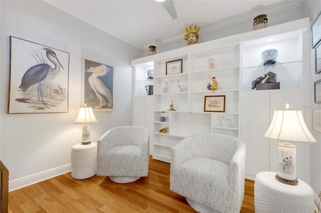 living area featuring baseboards, crown molding, and wood finished floors