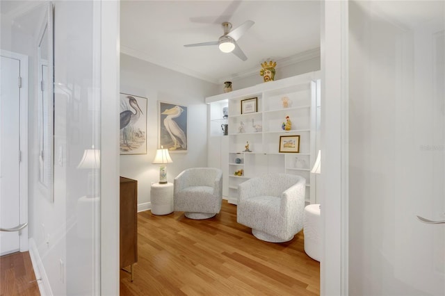 sitting room featuring light wood-style floors, ceiling fan, and crown molding