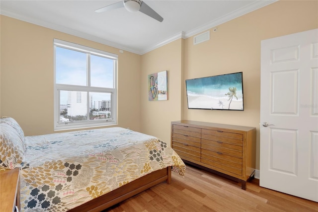 bedroom featuring baseboards, visible vents, a ceiling fan, wood finished floors, and crown molding