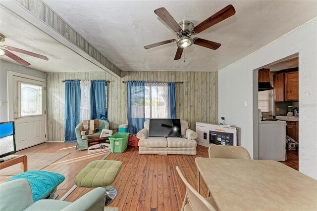 living room with light wood-type flooring, washer / clothes dryer, ceiling fan, and a wealth of natural light