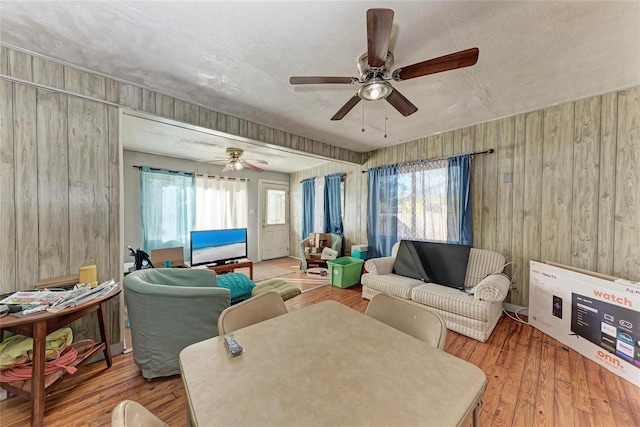 living room with hardwood / wood-style floors, wood walls, and a healthy amount of sunlight