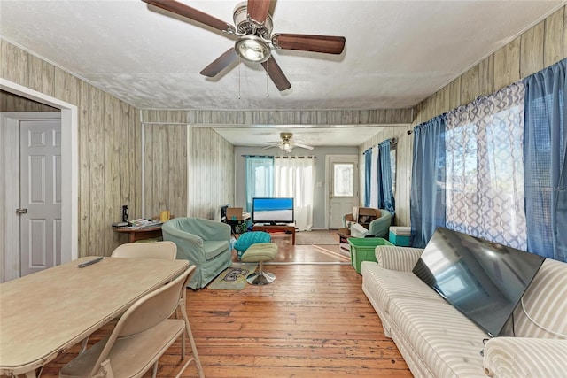 living room with wooden walls, ceiling fan, and wood-type flooring