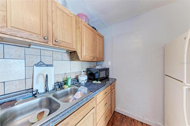 kitchen with white refrigerator, sink, backsplash, and light brown cabinetry