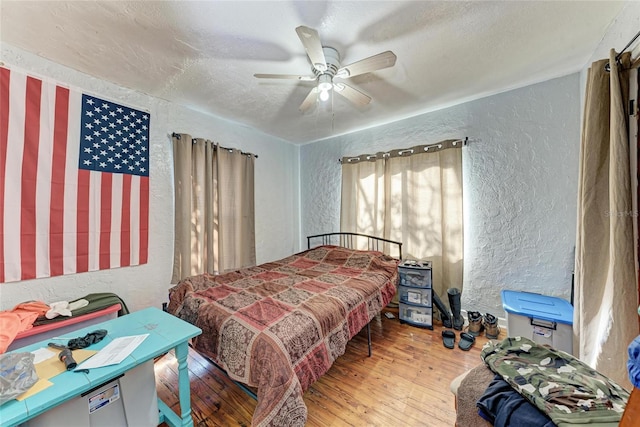 bedroom featuring hardwood / wood-style floors, ceiling fan, and a textured ceiling