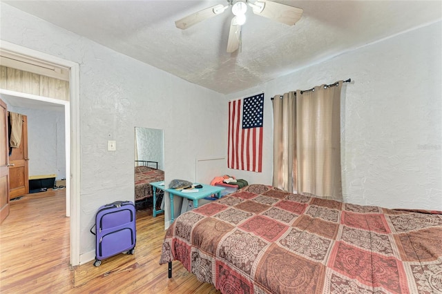 bedroom with ceiling fan, a textured ceiling, and hardwood / wood-style floors