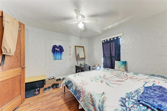 bedroom with a textured ceiling, hardwood / wood-style floors, and ceiling fan