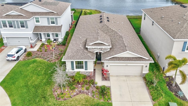 view of front of property with concrete driveway, a shingled roof, stucco siding, and a water view